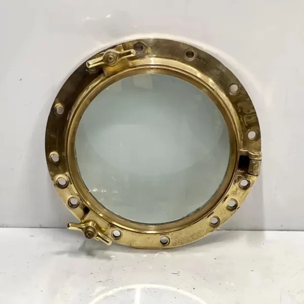 Solid brass ship porthole window with clear glass and hinged locking lugs – authentic nautical wall décor and marine mirror frame.