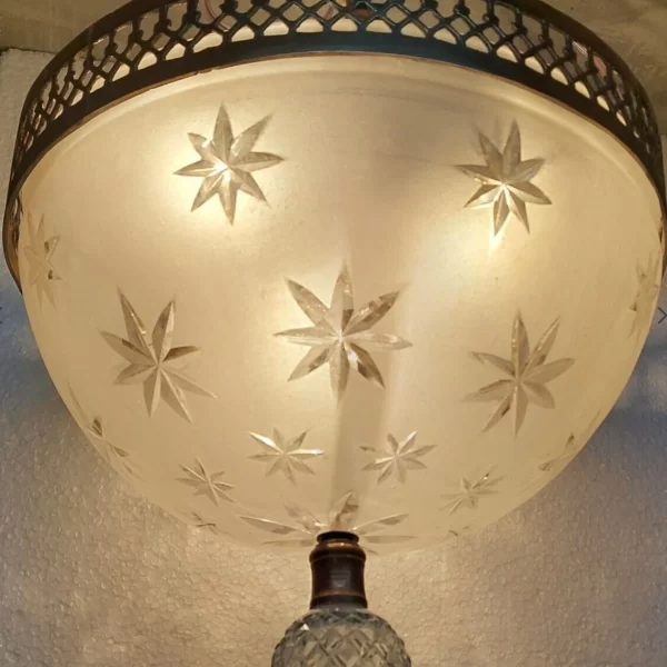 Antique brass Art Deco ceiling light with frosted glass shade etched with star patterns and crystal drop finial.